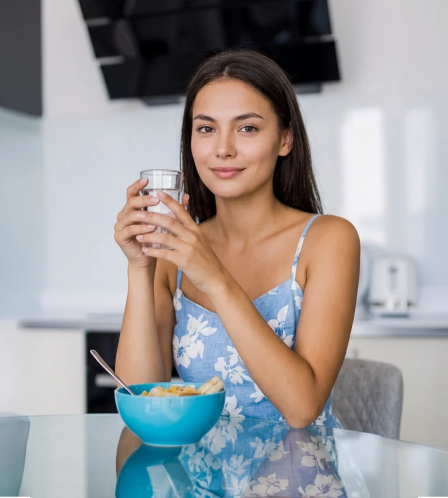 Woman drinking clean filtered water at home to reduce hard water minerals and improve water quality for everyday use.