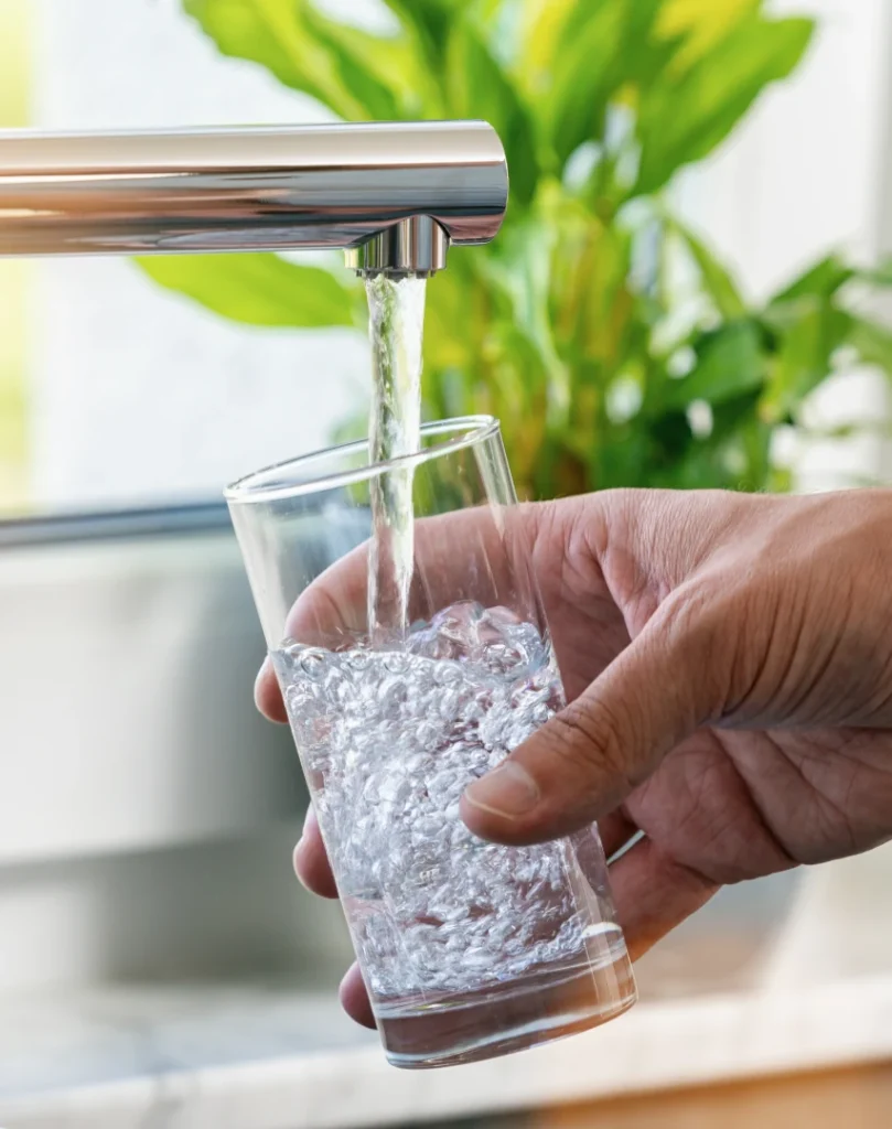 Clean drinking water poured from a kitchen tap into a glass, representing about Armour Water Filtration and their commitment to safe, purified water.